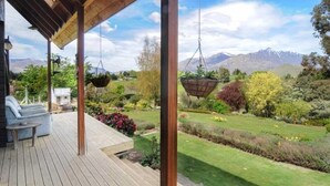 Een houten terras met hangende plantenbakken, een bank en een tafel.