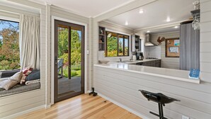 Een moderne keuken met een groot raam, een schuifpui naar een terras en een inbouwwalkbank met kussens.
