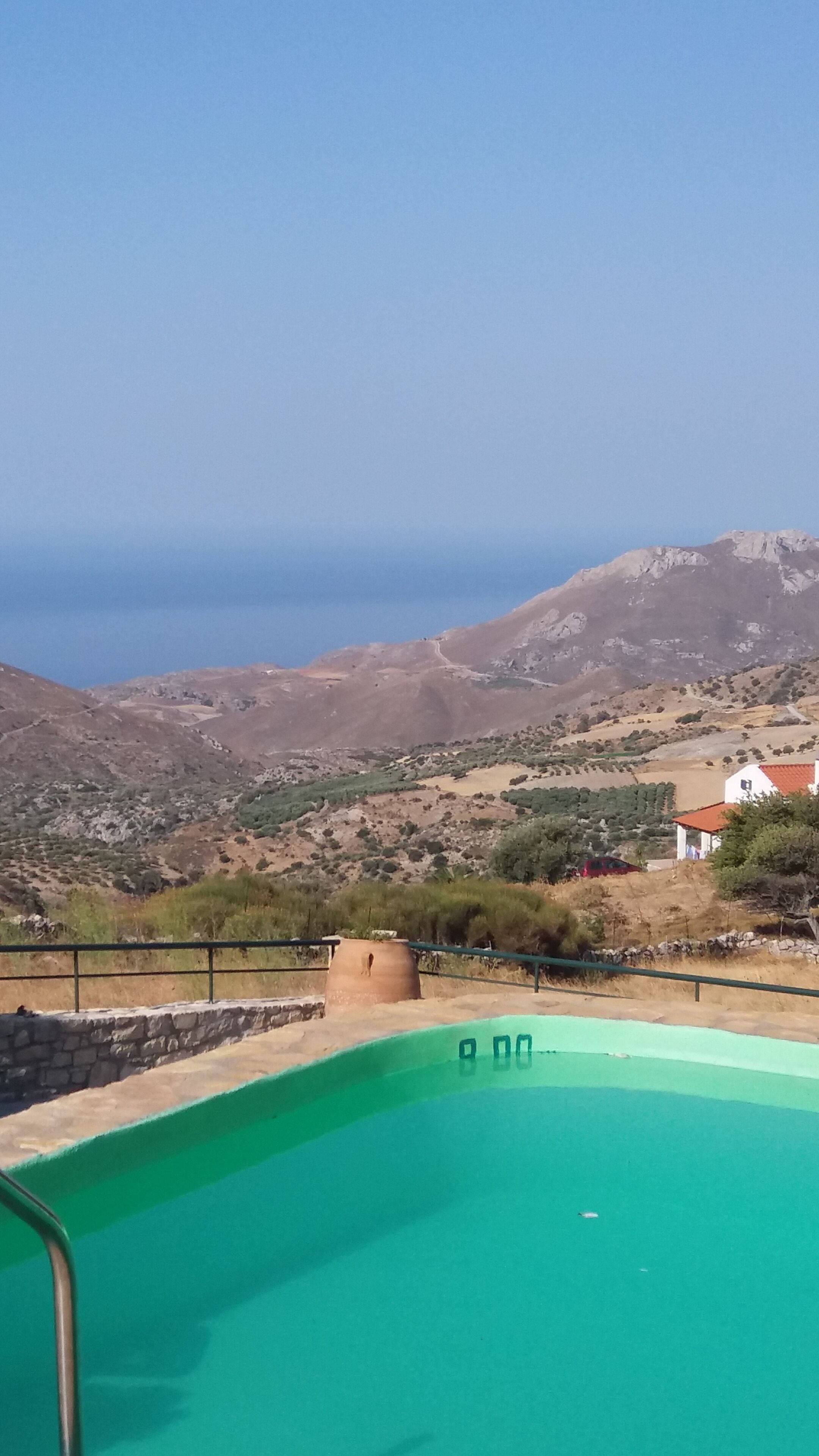 A swimming pool with a view of the sea and mountains.