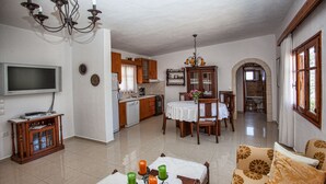 Un salon spacieux avec un canapé, une table à manger décorée de bougies et une cuisine en arrière-plan.