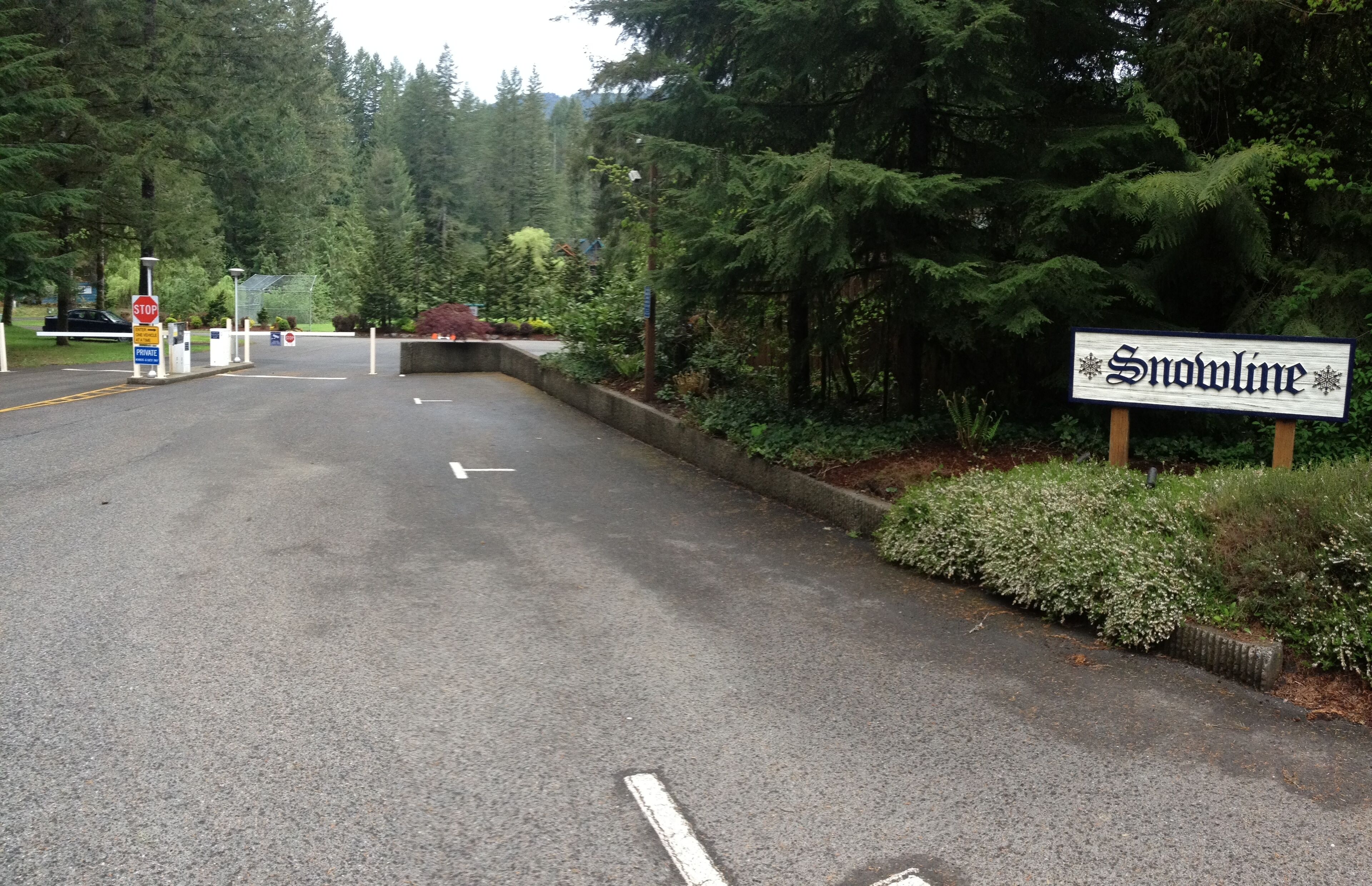 Une route menant à un panneau indiquant « Snowline », avec un panneau de signalisation de stop et un panneau indiquant un espace de stationnement à proximité.