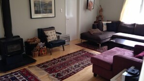 Un salon avec un canapé, un fauteuil, une cheminée et un tapis.