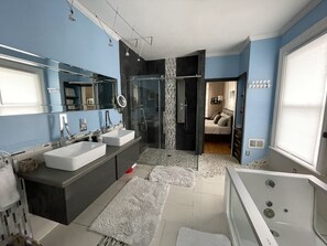 Een bad/douchecombinatie, een bubbelbad, een haardroger, handdoeken