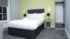 A neatly arranged hotel room with a large bed, bedside lamps, a wardrobe, and a window. - Spring Bank ApartHotel (Preston)