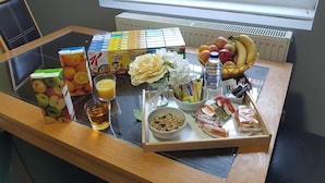 A breakfast tray with cereal, fruits, a bottle of water, and a glass of juice on a table near a window. - Spring Bank ApartHotel (Preston)