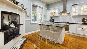 A kitchen with a fireplace, bar stools, and a large island.