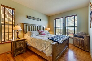 Um quarto com uma cama de madeira, duas mesas de cabeceira com luminárias, uma janela com persianas e uma placa de boas-vindas na parede.