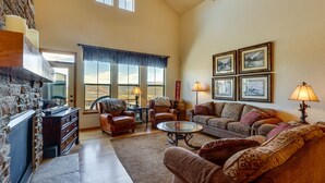 A spacious living room with a stone fireplace, leather armchairs, a sofa, and a coffee table. - 1 Mi to Granby Ranch: Mtn Home w/ Deck (Granby)