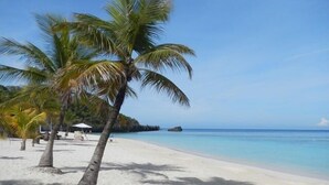 A beach with white sand, palm trees, and clear blue water. - Luxury 2 Bedroom, 2.5 Bath Dream Rental In West Bay (West Bay)
