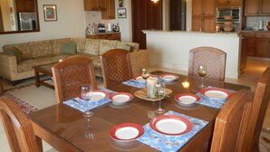 A dining area with a wooden table set for six, surrounded by wicker chairs. - Luxury 2 Bedroom, 2.5 Bath Dream Rental In West Bay (West Bay)