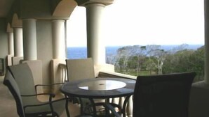 A covered outdoor seating area with a table and chairs, overlooking a mountainous landscape. - Luxury 2 Bedroom, 2.5 Bath Dream Rental In West Bay (West Bay)