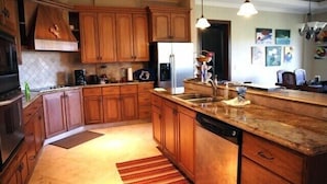 A kitchen with wooden cabinets, a stainless steel refrigerator, a granite countertop, and a built-in dishwasher. - Luxury 2 Bedroom, 2.5 Bath Dream Rental In West Bay (West Bay)