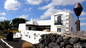 Un edificio blanco con fachada de piedra, un balcón y una estructura cónica distintiva.