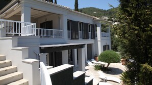 A two-story building with a balcony, outdoor seating, and a view of the surrounding landscape. - Villa Agni, Contemporary villa in excellent location just 200 meters from Agni Beach (Agni Beach)