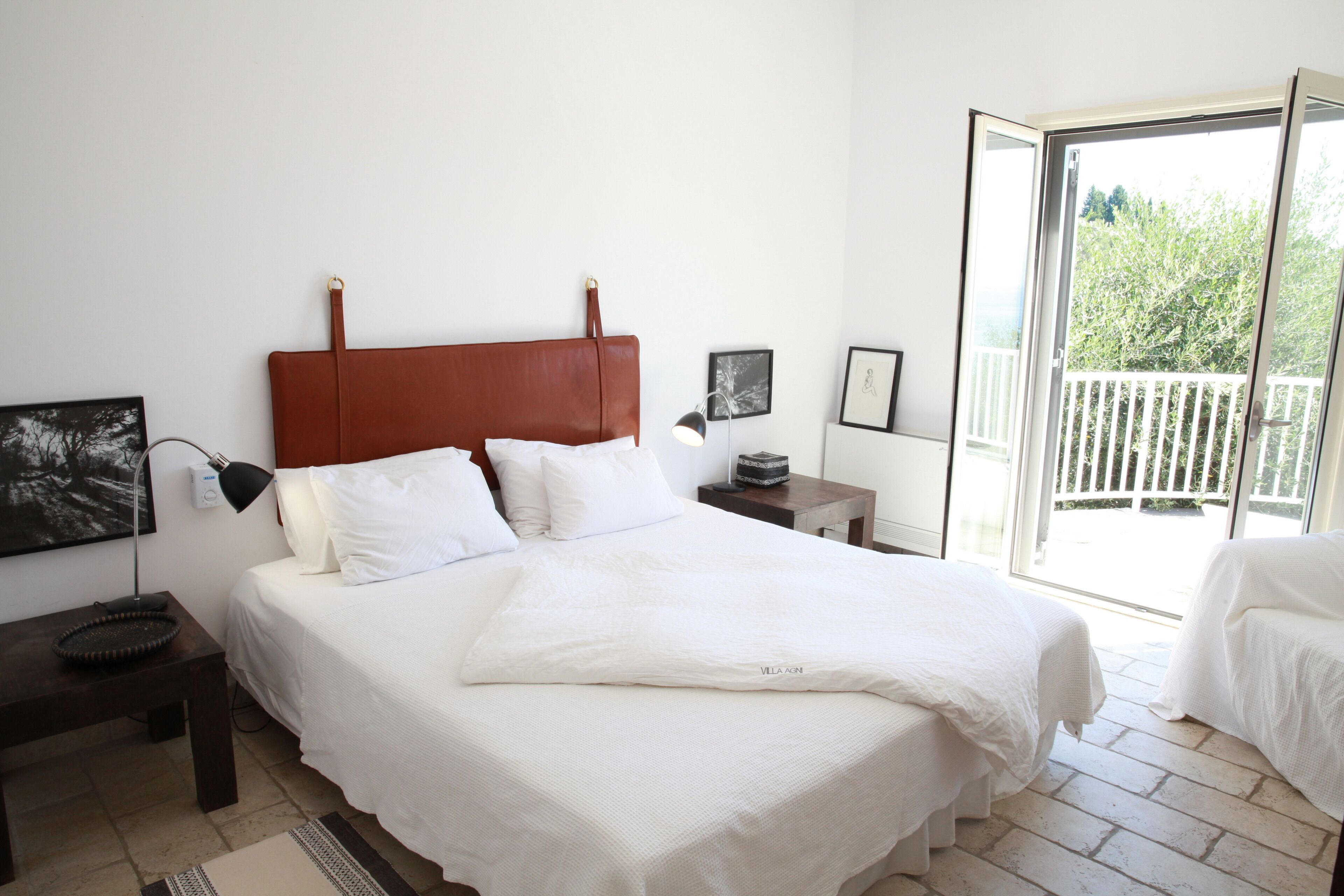 Une chambre avec un grand lit, une table de chevet, une lampe et une vue sur l’extérieur grâce à une porte coulissante.