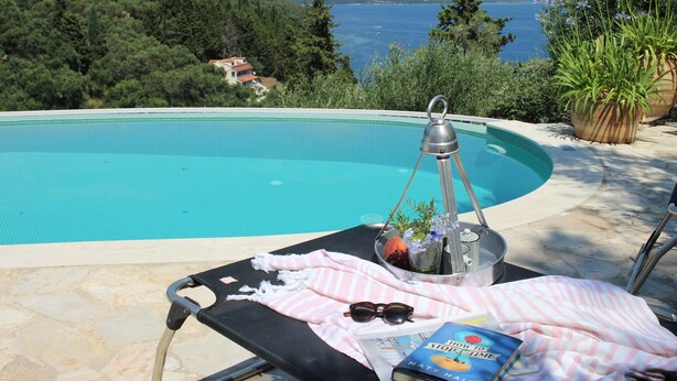 A poolside lounge with a view of the sea, a lounge chair, a book, and a bucket with flowers and a drink. - Villa Agni, Contemporary villa in excellent location just 200 meters from Agni Beach (Agni Beach)