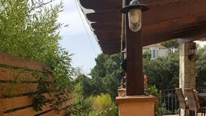 A covered outdoor area with a pergola, a stone pillar, and a table with chairs. - Blanes: beautiful house with pool and garden (Blanes)