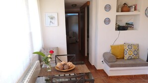 A cozy living area with a dining table, a sofa, and a wall-mounted shelf with decorative items. - Blanes: beautiful house with pool and garden (Blanes)