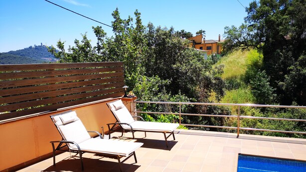 A poolside area with two sun loungers and a wooden fence. - Blanes: beautiful house with pool and garden (Blanes)