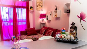 A cozy living room with a red sofa, a coffee table, and a decorative wall with a pink flower. - Apartment in 1 sea line (tabaiba)