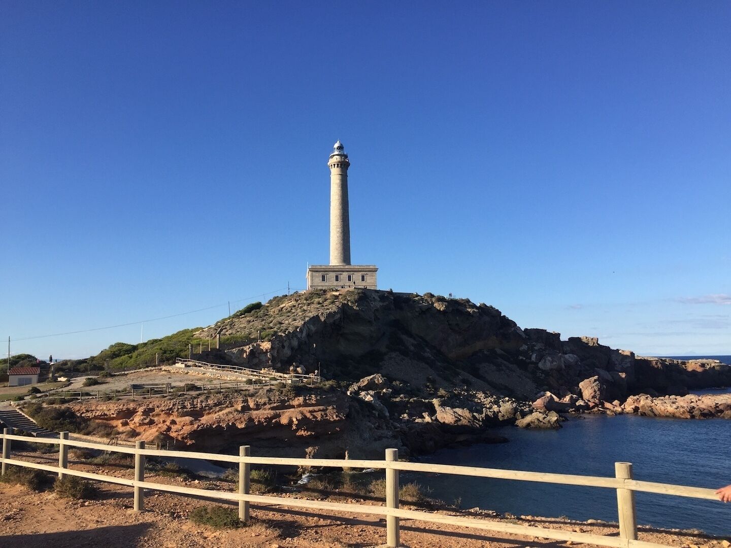 Un faro sobre un promontorio rocoso con una vista despejada del paisaje circundante y el agua.