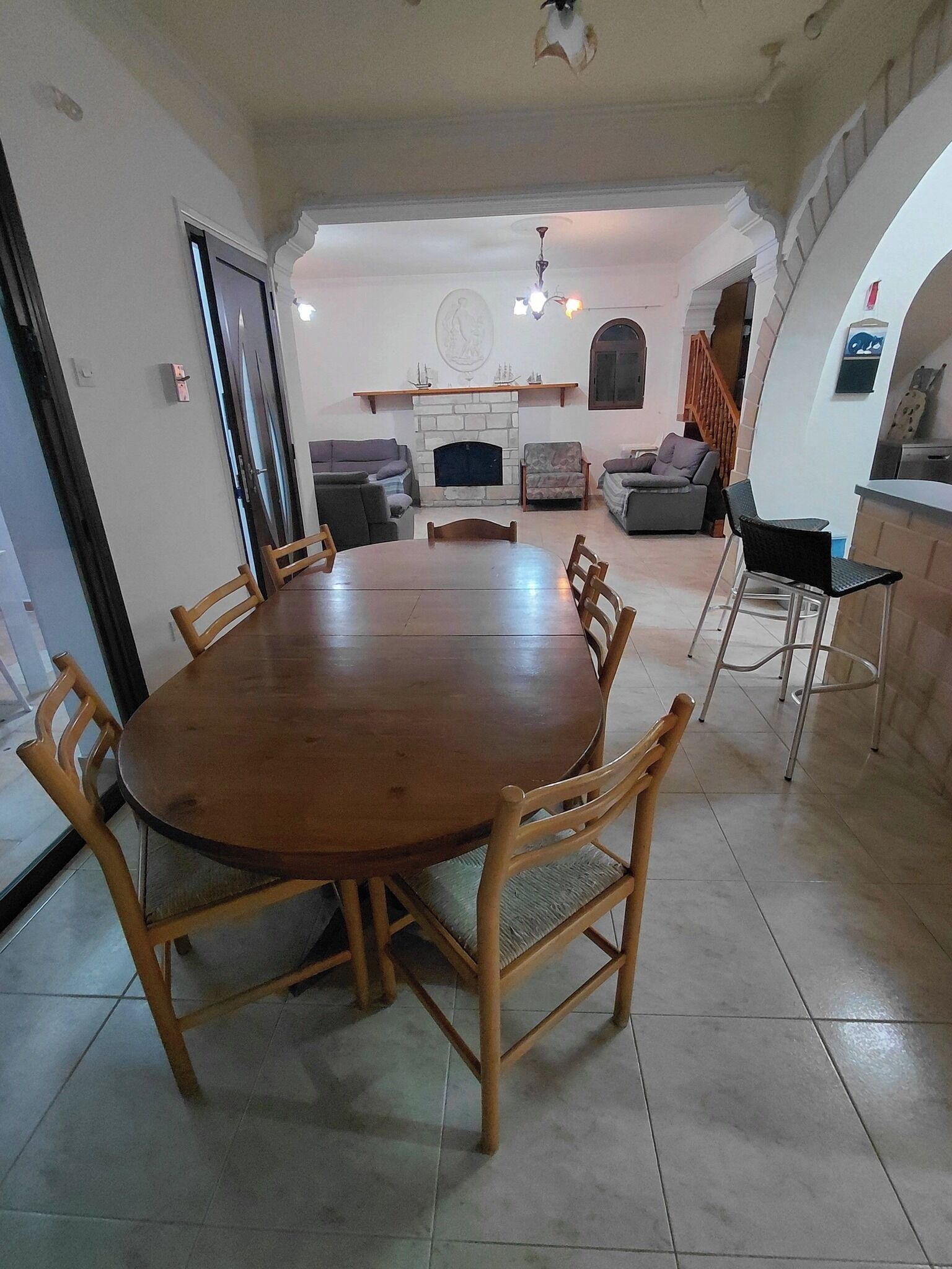 Un espace repas avec une table ronde en bois entourée de chaises, une cheminée et un escalier menant à un autre niveau.