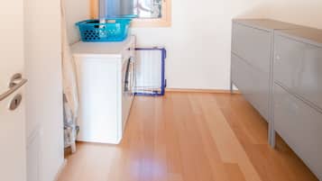 Eine kleine Küche mit Waschmaschine, Wäscheständer und einem grauen Schrank.