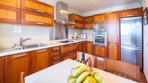 Una cocina moderna con armarios de madera, electrodomésticos de acero inoxidable y una isla central con frutas frescas.