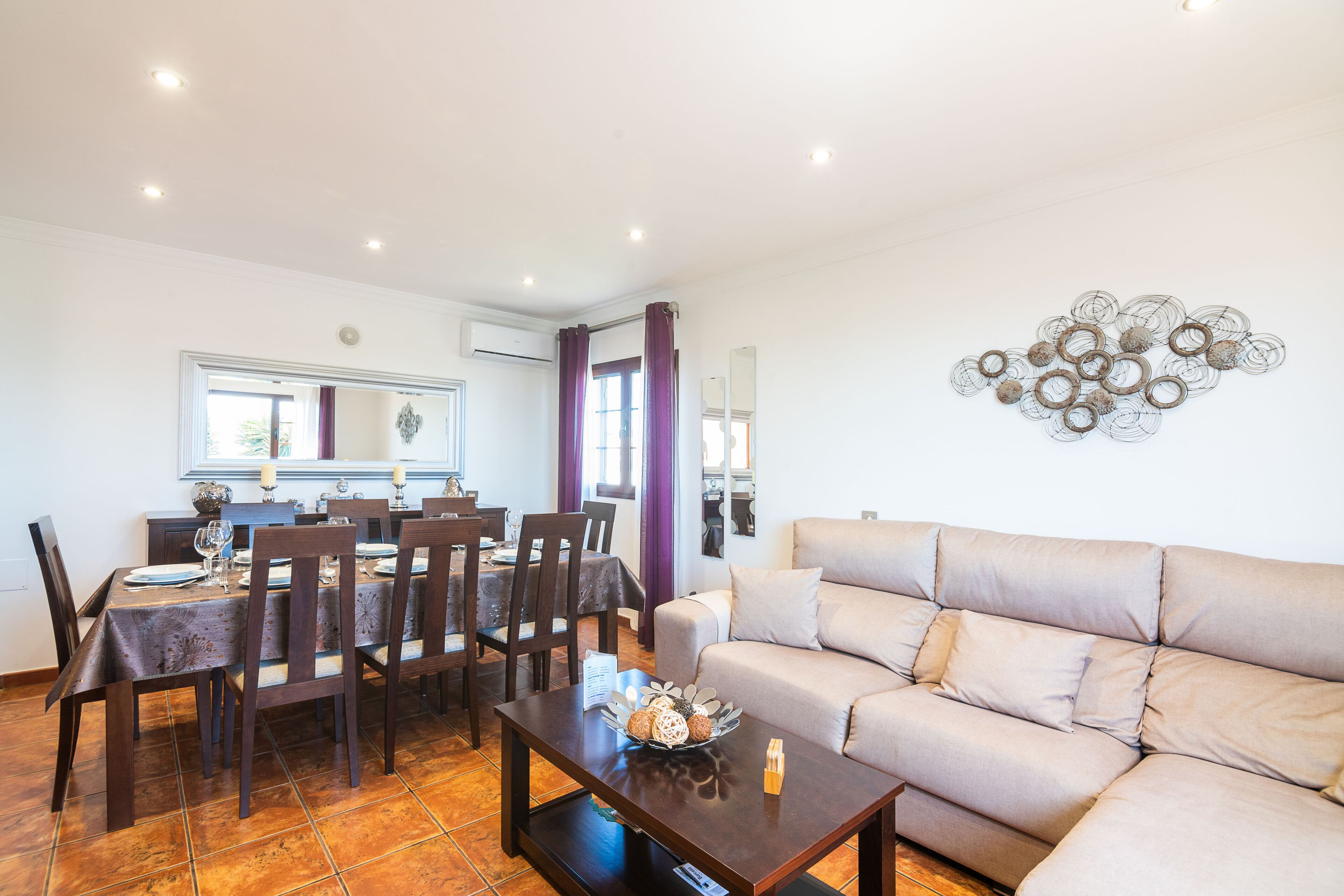 A dining area with a table set for four, a sofa, and a decorative wall piece.