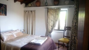 A bedroom with a bed, a chair, a window with patterned curtains, and a vase on the wall. - Pretty holiday cottage with private pool, fantastic views sleeps 6, Arganil 7kms (Arganil)