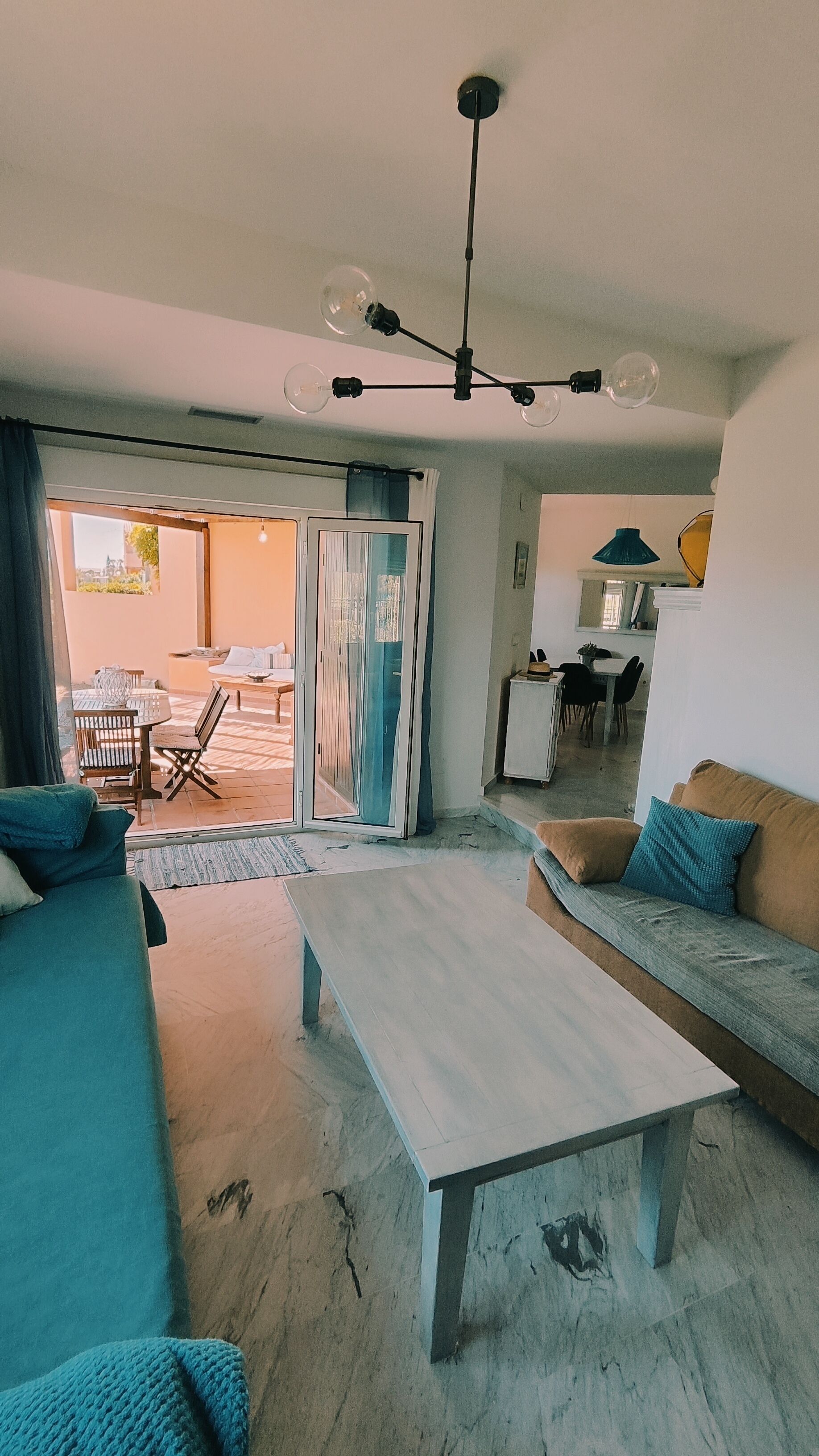 A modern living room with a sofa, a coffee table, and a dining area with chairs and a table.