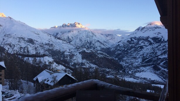 Un paysage montagneux enneigé avec une cabane et un sommet de montagne en arrière-plan.
