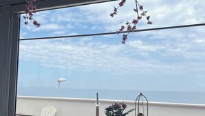 A table set with a candle, a glass, and a flower arrangement on a balcony with a view of the sea. - Palese Profumo di Mare (Bari)
