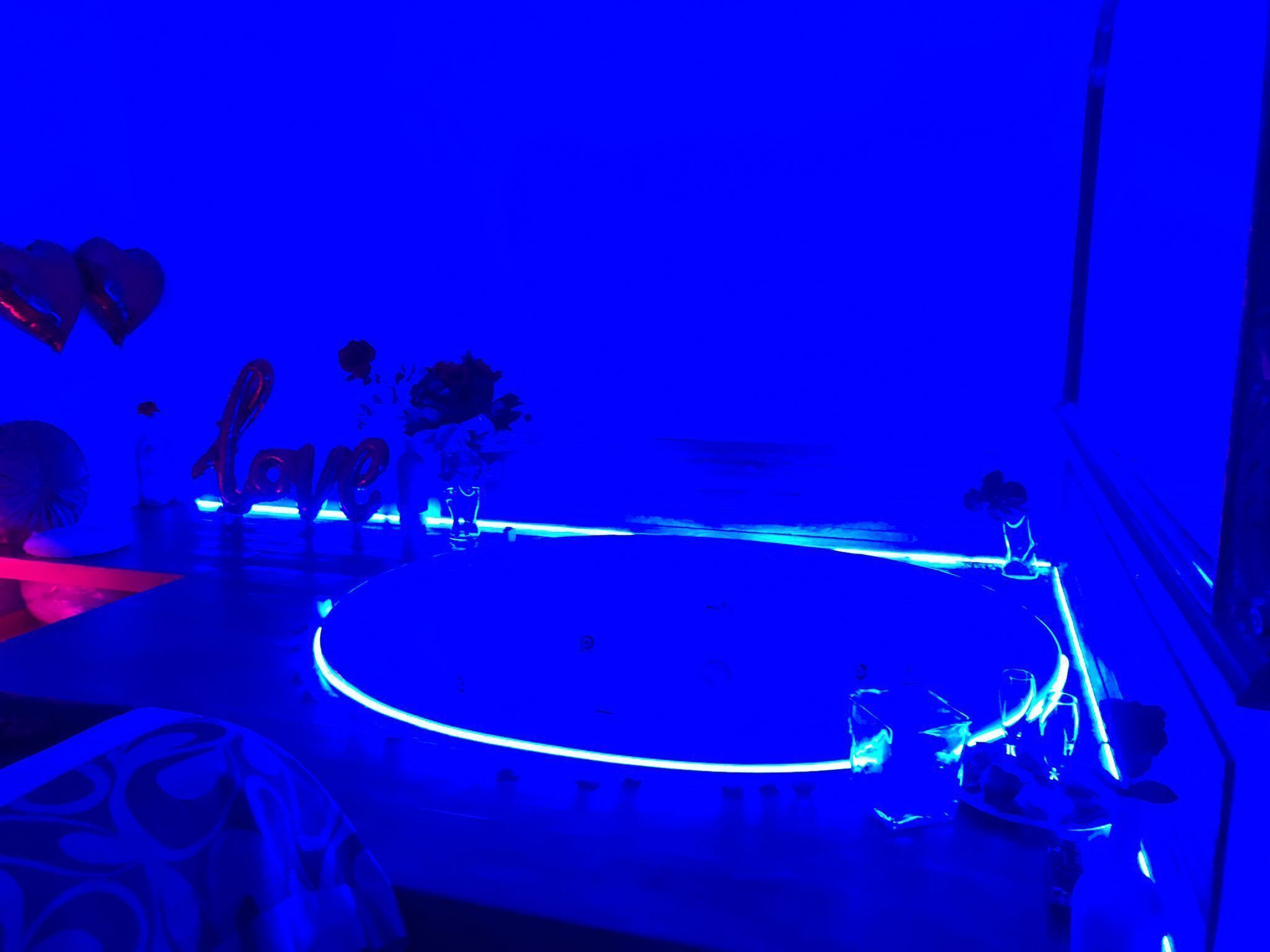 A dimly lit room with a circular table, a few chairs, and a vase with flowers.