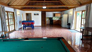 Un espacio interior amplio con mesa de billar, mesa de fútbol de mesa y zona de cocina.