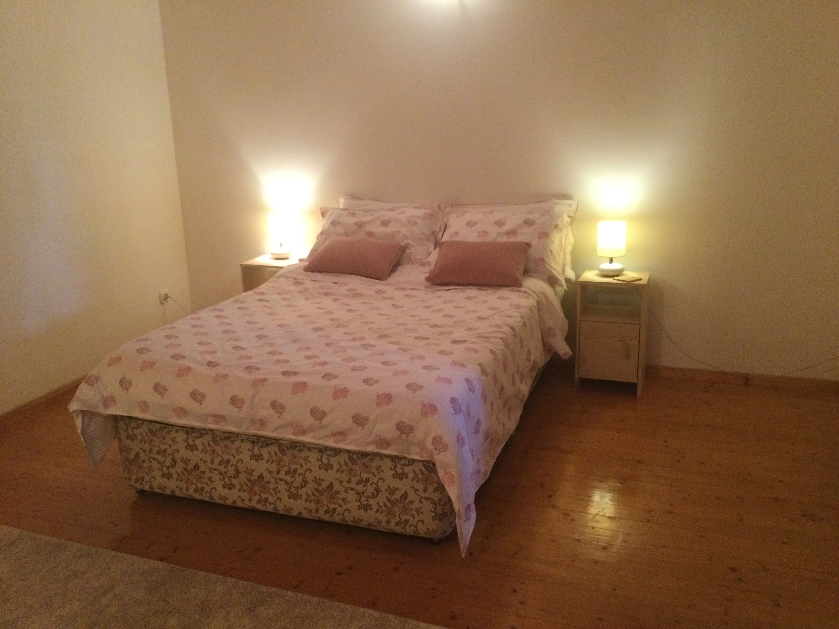 Un dormitorio con una cama, dos mesitas de noche y dos lámparas.