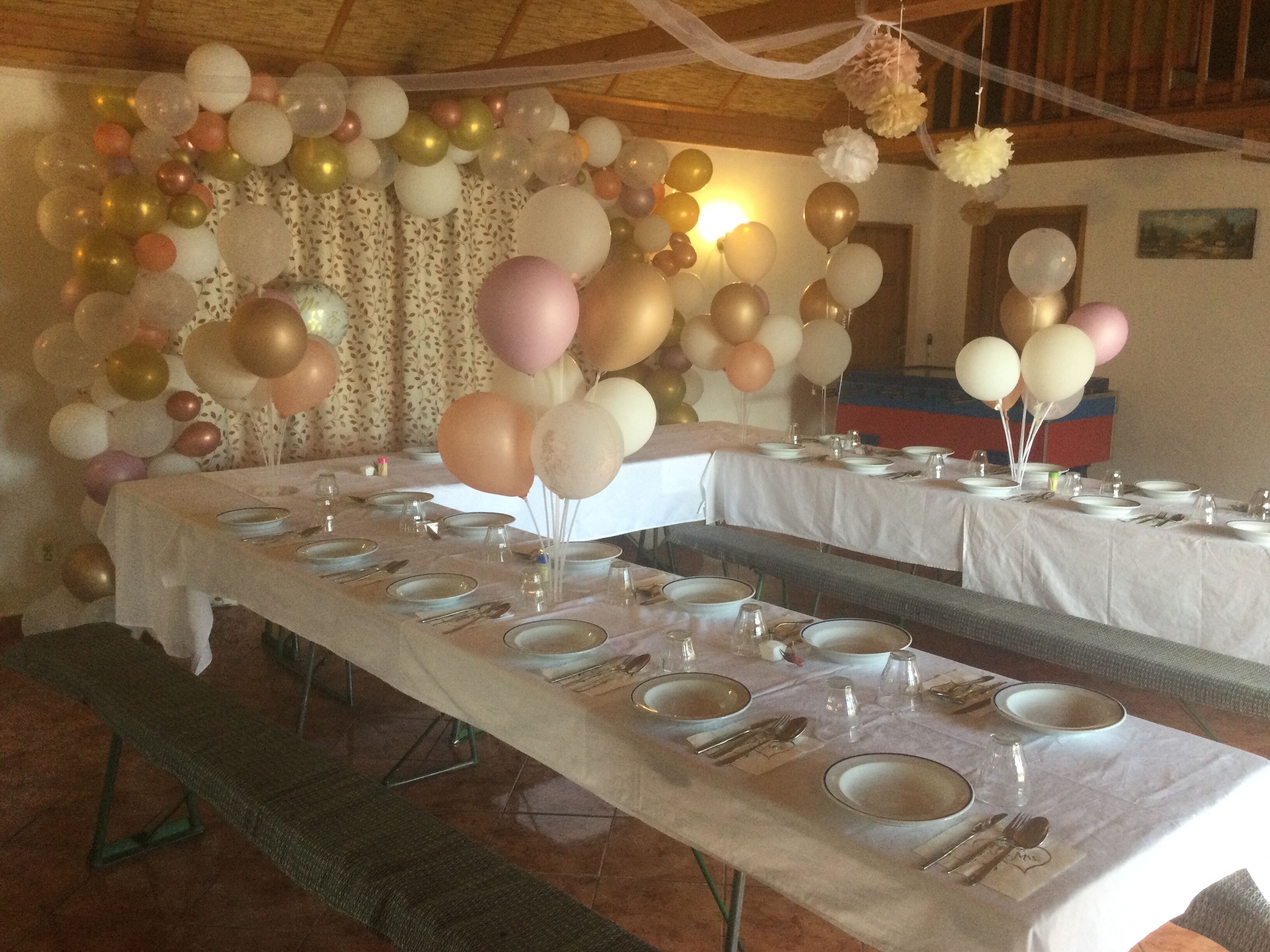 Une salle de banquet où les tables sont dressées pour un événement officiel, décorées de ballons et d’un arrangement floral.