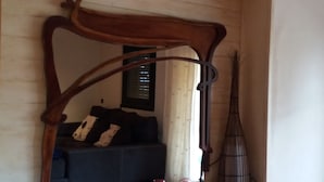 A room with a dark-colored sofa, a standing lamp, and a mirror reflecting a window with blinds. - All - in! Villa with view, pool, quiet and private. Last-minute in september (Tordera)