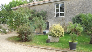 Un bâtiment en pierre avec un toit en tuiles, une fenêtre et une allée gravillonnée.