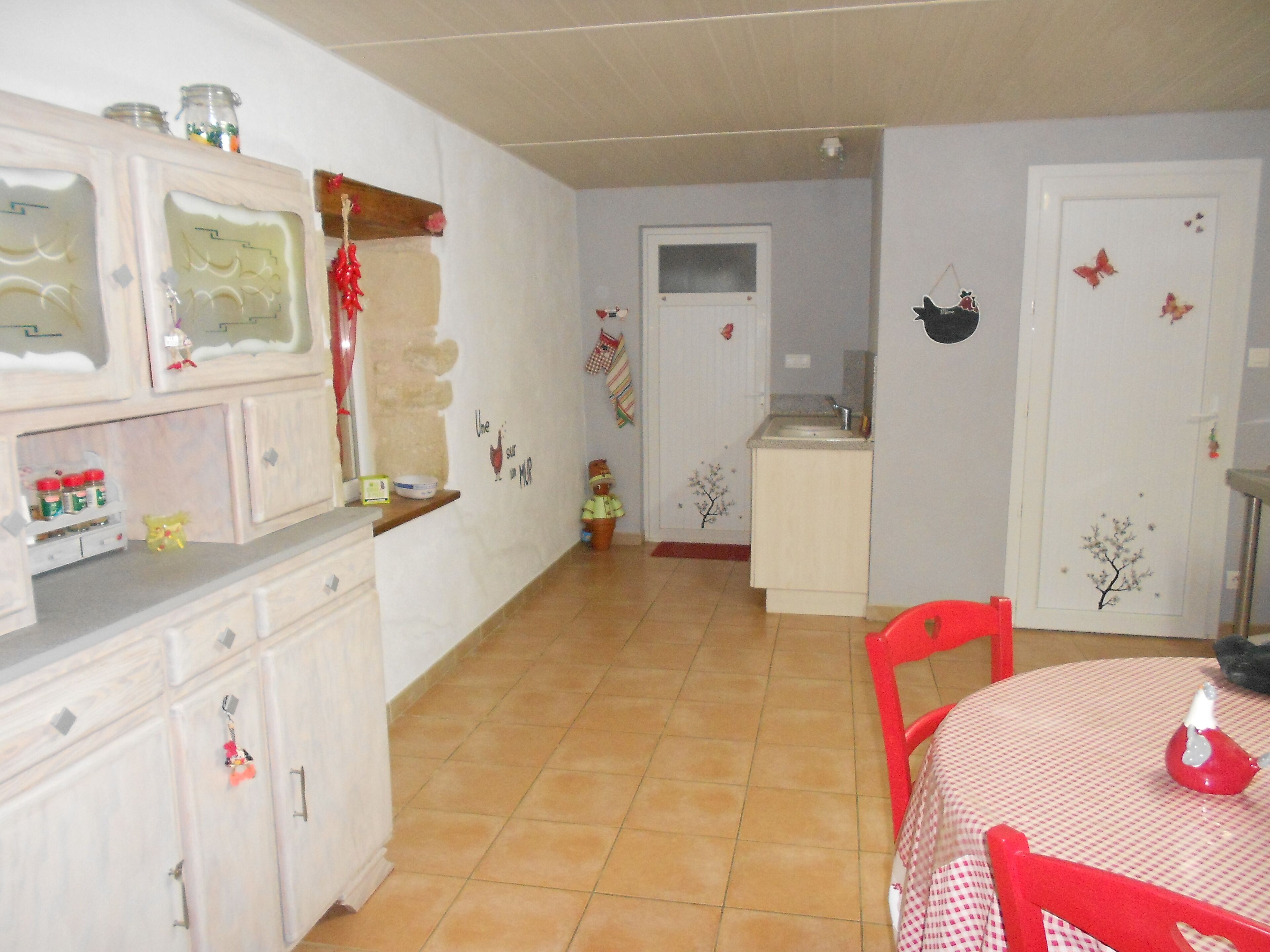 A kitchen with white cabinets, a red chair, and a table with a red tablecloth.