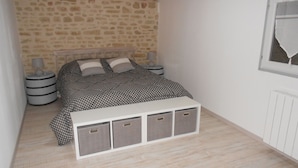 Une chambre à coucher comprenant un lit, une table de chevet, une lampe et un meuble de rangement.