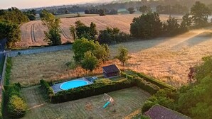Ovenudblik over en ejendom med swimmingpool, legeplads og en indhegnet have.