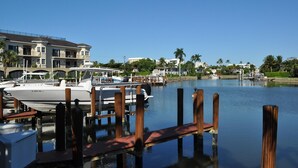 Un puerto deportivo con barcos amarrados, un muelle de madera y un edificio grande con balcones al fondo.