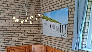 Ein Essbereich mit Holztisch und Bank, einer Ziegelwand und einem Gemälde mit Strandmotiv.