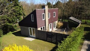 Ein modernes, zweistöckiges Haus mit einem geneigten Dach, einem Schornstein und einem umzäunten Garten.