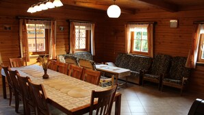 A wooden cabin with a dining table set for six, surrounded by chairs, and a sofa with patterned cushions.