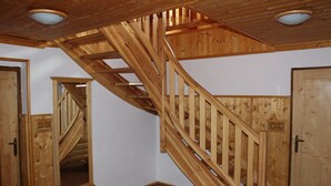 A wooden staircase with a handrail, connecting two rooms with white walls and wooden doors.