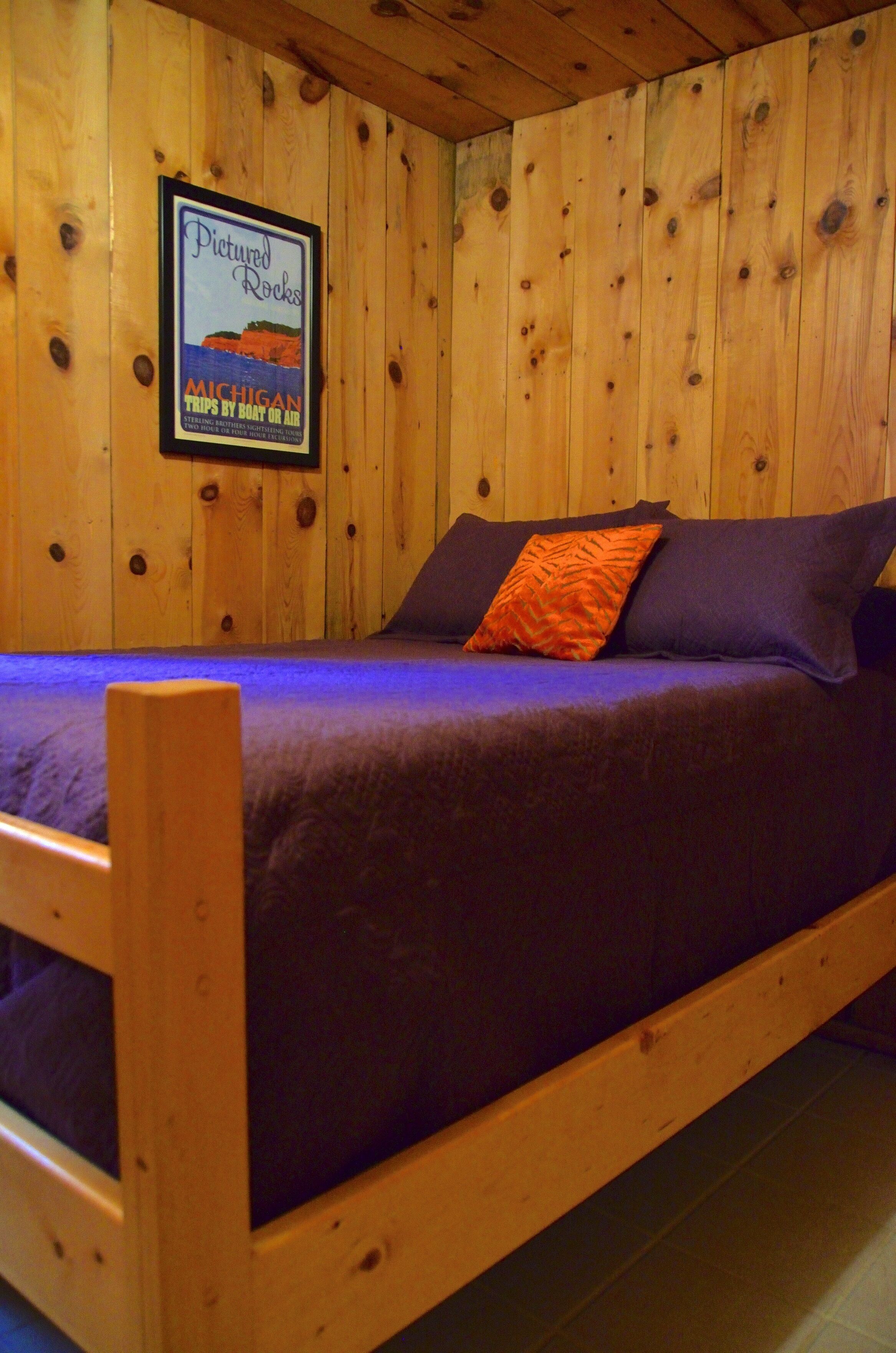 A wooden bunk bed with a framed poster on the wall.