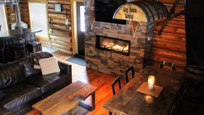 A cozy log cabin interior with a stone fireplace, wooden furniture, and a rustic ambiance.