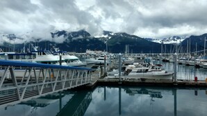 Un puerto deportivo con barcos amarrados, un puente y montañas al fondo.